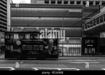 Ein Double Decker Straßenbahn (Ding Ding) vorbei vor der Hermes Shop. Hong Kong, Zentrale, Januar 2018 Stockfoto