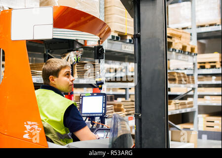 Junger Mann in Arbeitskleidung, Treiber Schubmaststapler arbeitet auf der Logistik Lager store Stockfoto