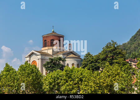 Laveno, Italien, 6. Juli 2013: Blick auf Sant Ambroggio Kirche vor blauem Himmel und umgeben von Bäumen. Stockfoto