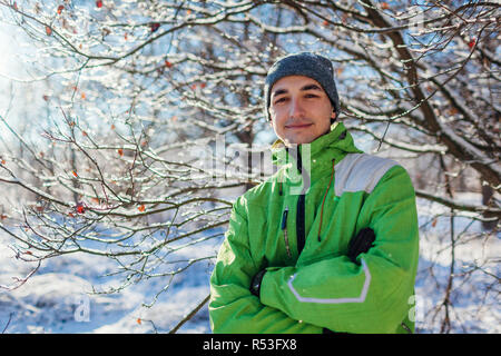 Junger Mann tragen sportliche Kleidung im Winter Wald. Lächelnd Kerl an der Kamera, die in die Hände gekreuzt Stockfoto