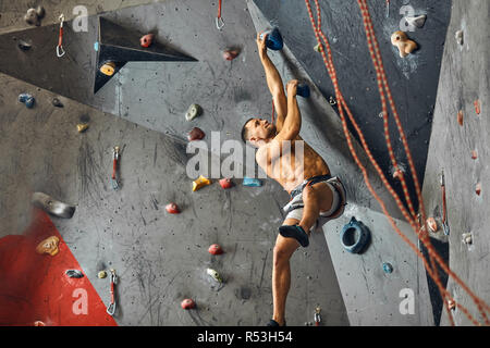 Panoramablick mann Bouldern in einer Kletterhalle. Stockfoto