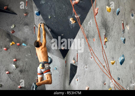 Panoramablick mann Bouldern in einer Kletterhalle. Stockfoto