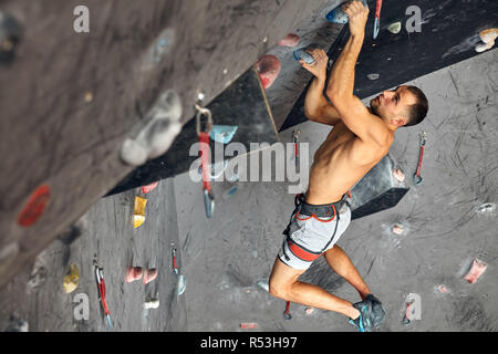 Männliche professioneller Bergsteiger an Indoor Training zu Bouldern. Stockfoto