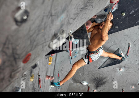 Männliche professioneller Bergsteiger an Indoor Training zu Bouldern. Stockfoto