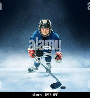 Little boy Eishockey in der Arena. Ein Hockeyspieler in Uniform mit Ausrüstung über einen blauen Hintergrund. Der Athlet, Kind, sport, action concept Stockfoto