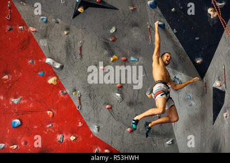 Männliche professioneller Bergsteiger an Indoor Training zu Bouldern. Stockfoto