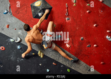 Männliche professioneller Bergsteiger an Indoor Training zu Bouldern. Stockfoto