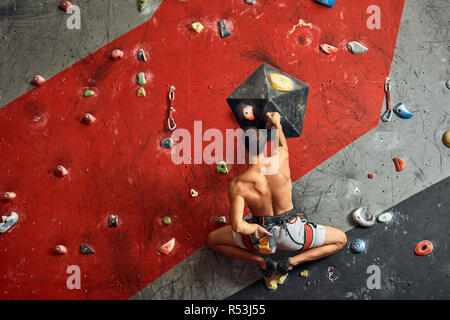 Männliche professioneller Bergsteiger an Indoor Training zu Bouldern. Stockfoto