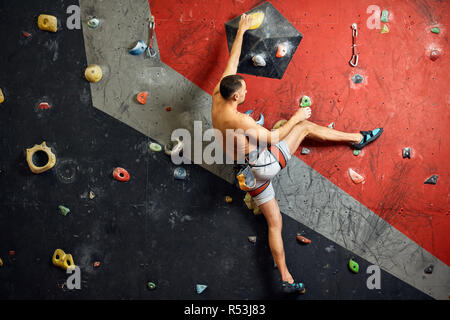 Männliche professioneller Bergsteiger an Indoor Training zu Bouldern. Stockfoto