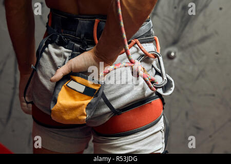 Kletterer s männliche Hände mit Ausrüstung während der Vorbereitung für Klettern, close-up.