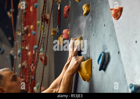 Makroaufnahme der Kletterer Hände greifen bunte Haltegriffe während Indoor Training Stockfoto