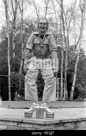 Elton John, Sänger, dargestellt in Virginia Water, 1973. Er spielt für die Kamera, über 3 Bilder, Gesichter ziehen und zeigt seinen haarigen Beinen und neueste Plattform Stiefel, die eine 5-Plattform Größe, und 8 Zoll hoch. Sie sind Silber und Rot, mit Seine Initialen auf, und gebildet wurden, in etwa drei Tagen von Ken Todd von Kensington Market zu messen. Bild März 1973 20. Stockfoto