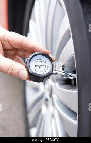 Nahaufnahme des Mannes Auto Reifendruck mit Manometer überprüfen Stockfoto