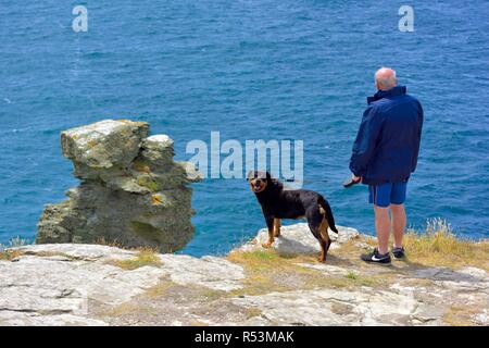 Ein Mann seinen Rottweiler Hund auf der Insel Halbinsel Tintagel, Cornwall, England, Großbritannien Stockfoto