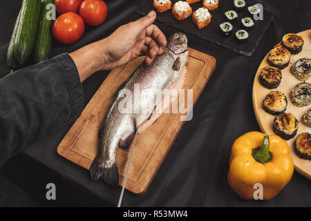 Des Menschen Hände schneiden Fischfilet im Restaurant Stockfoto