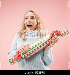 Die überraschte Frau mit großen bunten Geschenkbox. Sanfte Farben. Weihnachten, Geburtstag, Valentinstag, Geschenke. Studio Portrait über rosa Hintergrund Stockfoto