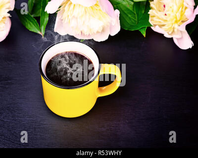 Kaffee in einem gelben Becher auf eine schwarze Fläche Stockfoto