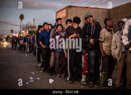 Tijuana, Mexiko. 28 Nov, 2018. Migrantinnen und Migranten sind Schlange zu einem Essen. Dutzende von Migrantinnen aus Mittelamerika haben freiwillig aus Mexiko in ihre Heimatländer zurückgekehrt, nach etwa zwei Wochen an der US-Grenze. Credit: Omar Martinez/dpa/Alamy leben Nachrichten Stockfoto