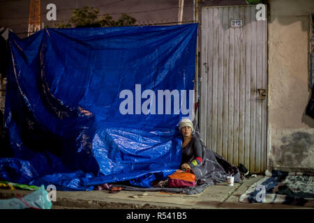 Tijuana, Mexiko. 28 Nov, 2018. Ein Wanderarbeitnehmer sitzt auf der Straße vor dem Benito Juarez Sports Complex, die als Notunterkunft für Migranten dient. Dutzende von Migrantinnen aus Mittelamerika haben freiwillig aus Mexiko in ihre Heimatländer zurückgekehrt, nach etwa zwei Wochen an der US-Grenze. Credit: Omar Martinez/dpa/Alamy leben Nachrichten Stockfoto