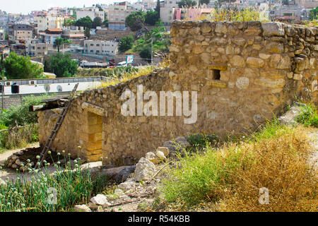 Retro Style Steinhaus im Freilichtmuseum von Nazareth Village Israel. Häuser in der modernen Nazareth im Hintergrund gesehen werden kann. Diese Seite gi Stockfoto