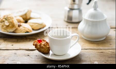 Frisch Kaffee in ein weißes Porzellan Schale auf dem Holztisch gemacht mit einem Kuchen auf einer Seite Stockfoto