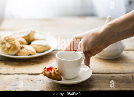 Frisch Kaffee in ein weißes Porzellan Schale auf dem Holztisch gemacht mit einem Kuchen auf einer Seite Stockfoto