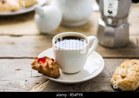 Frisch Kaffee in ein weißes Porzellan Schale auf dem Holztisch gemacht mit einem Kuchen auf einer Seite Stockfoto