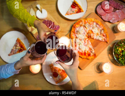 Tabelle mit verschiedenen Lebensmitteln mit Rotwein und Kerzen serviert. Ansicht von oben. Toast der Freunde Stockfoto