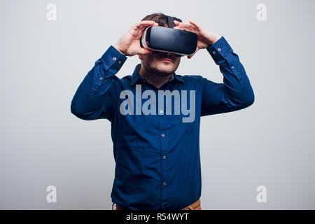Junger Mann mit VR-Brille Headset versucht, Objekte in der Virtuellen Realität zu berühren. Isoliert weißer Hintergrund. Stockfoto