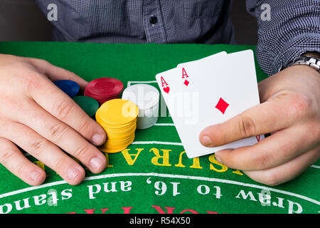Casino Chips und Karten am grünen Tisch. Mann mit zwei Asse in der Hand. Spielsucht abstraktes Konzept. Stockfoto