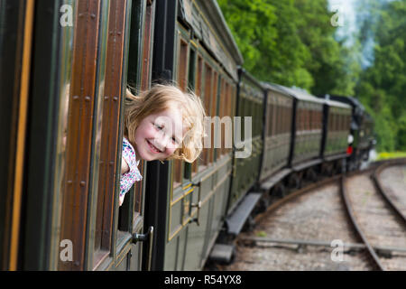 Passagier junge Mädchen im Alter von 8- 8 Jahre alt, lächelnd und Blick aus dem Fenster eines fahrenden Zuges Schlitten auf der Isle of Wight Steam Railway Line. UK. (98) Stockfoto