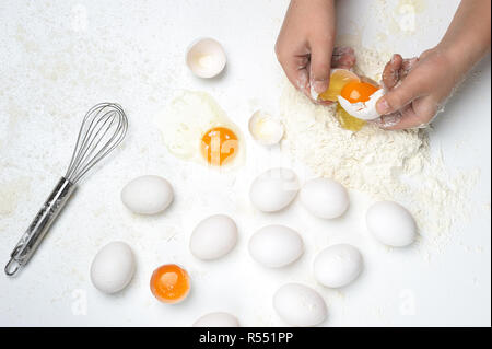 Grundlegende Bestandteile an die frische Pasta oder Teig mit nur Hände, Eier, Mehl, Whisker auf dem weißen Hintergrund. Mehl auf der Arbeitsfläche. Stockfoto