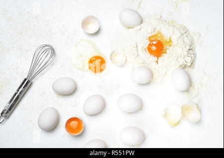 Grundlegende Bestandteile an die frische Pasta oder Teig mit nur Eier, Mehl, Whisker auf dem weißen Hintergrund. Mehl auf der Arbeitsfläche. Stockfoto