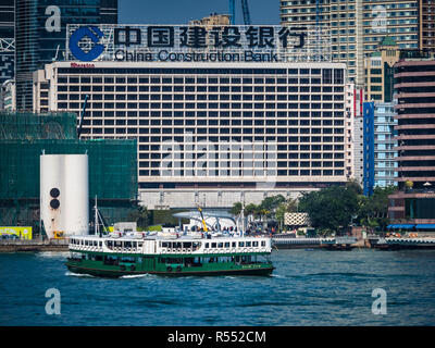 China Construction Bank Hongkong China - Star Ferry fährt vor der großen China Construction Bank Werbung auf der Kowloon-Seite des Victoria Harbour Stockfoto