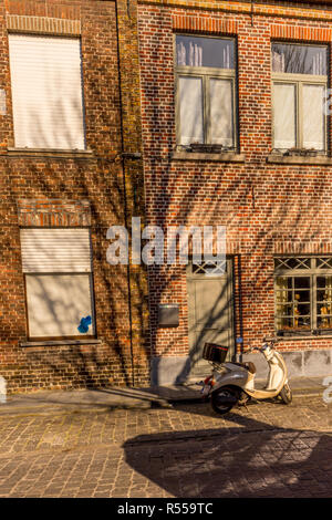 Brügge, Belgien - 17. Februar 2018: Weiß Vespa vor einem roten Backsteingebäude in Brügge/Belgien Brügge Stockfoto