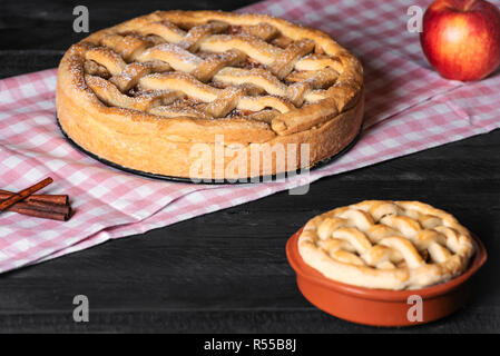 Rustikale Schwarzer Tisch mit frisch gebackenen Apfelkuchen, mit Puderzucker, auf einer rosa Handtuch. Hausgemachte süße Speisen. Köstliche Kuchen. Nationale pie Tag. Stockfoto