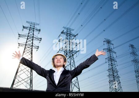 Geschäftsfrau vor Stromleitungen mit Armen oustretched Stockfoto