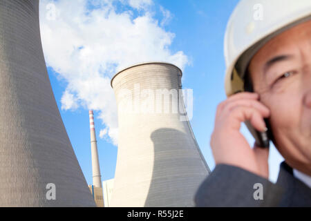 Geschäftsmann am Handy im Kraftwerk Stockfoto