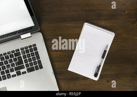 Draufsicht auf das Notebook und Notepad auf braunem Holz- Schreibtisch, Arbeitsbereich Konzept Stockfoto