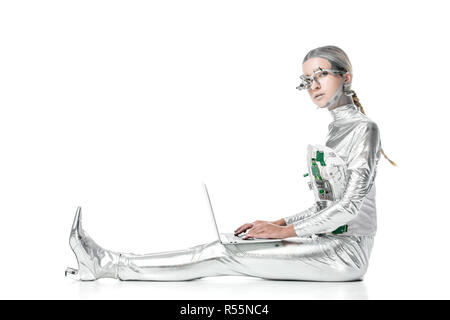 Seitenansicht von Silber Roboter sitzt mit Laptop und Kamera auf Weiß, zukünftige Technologie Konzept isoliert Stockfoto