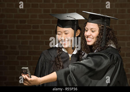 Zwei weibliche Absolventen mit dem Fotografieren Stockfoto