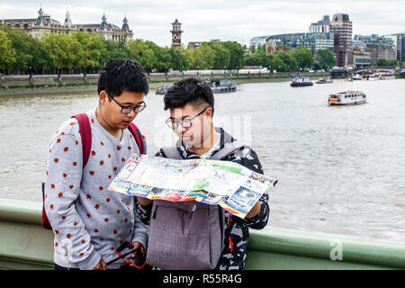 London England, Großbritannien, Westminster Bridge, Themse River, asiatischer Mann Männer männlich, junge Jungen, Kinder Kinder Kinder Jugendliche, Teenager Teenager Jugendliche lesen Stockfoto