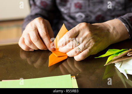 Die Hände der älteren Dame falten Origami Papier Stockfoto