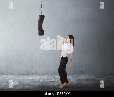 Junge asiatische Geschäft Frau schreiend mit einem Megaphon zu schwarz Empfänger Stockfoto