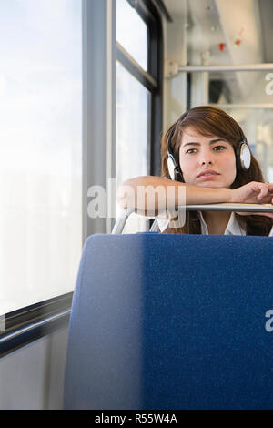 Frau mit Kopfhörern auf dem Zug Stockfoto