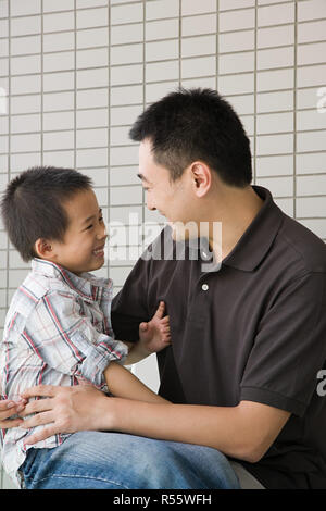 Junge sitzt auf seinem Schoß Väter Stockfoto