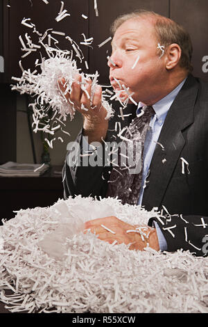 Reife Geschäftsmann spielen mit Papier Schreddern Stockfoto