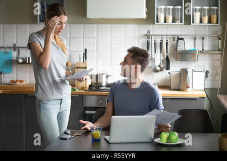 Zornigen Mann die Schuld Frau, Prüfung von Dokumenten, Rechnungen Stockfoto