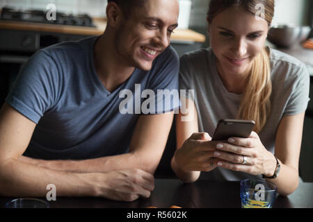 Junge lächelnde Ehepaar am Bildschirm des Smartphones auf der Suche Stockfoto
