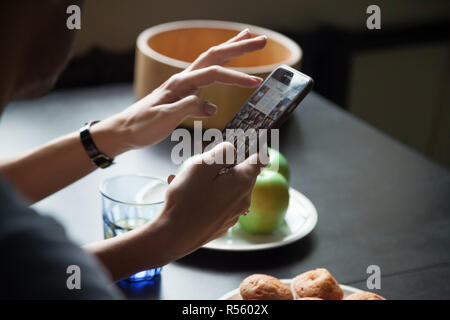 Weibliche Hände halten Smartphone und zeigt Fotos Stockfoto
